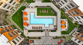 A swimming pool surrounded by orange chairs and a concrete patio.